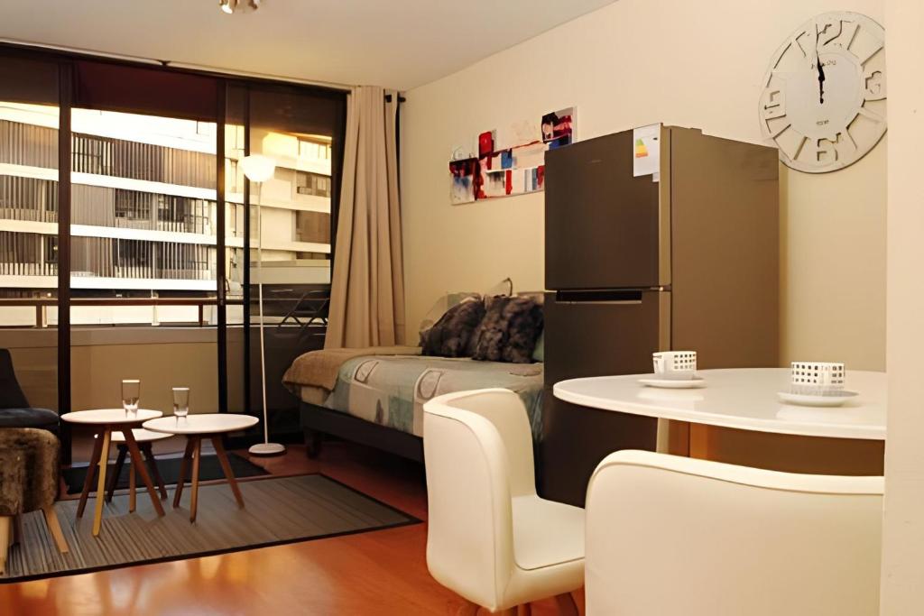 Habitación con cama, mesa y nevera. en Living Paris en Santiago