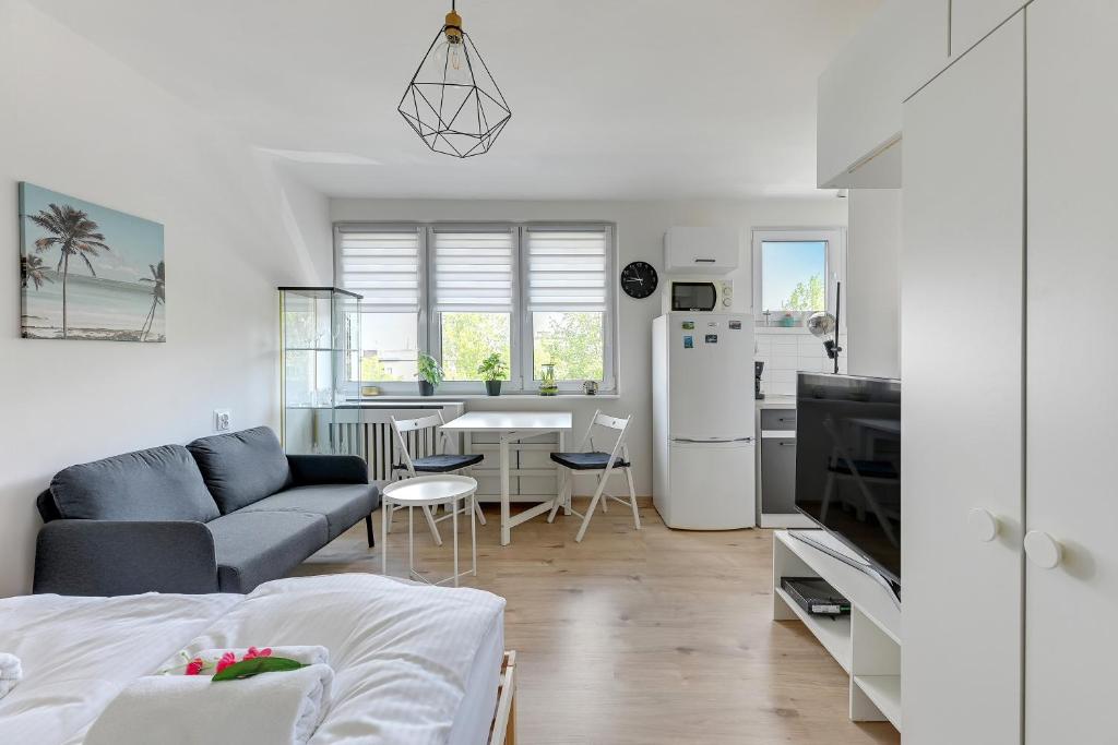 a white living room with a couch and a kitchen at Wave Apartments - Aurora in Gdynia