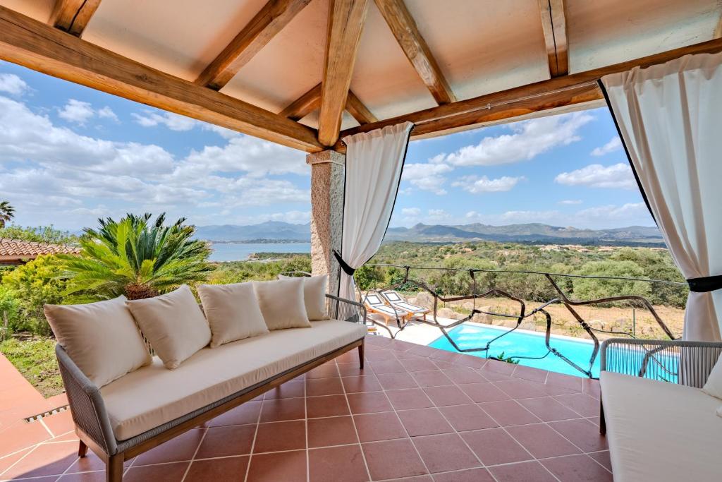 a porch with a couch and a view of the ocean at Villa Capo Coda Cavallo piscina privata in San Teodoro