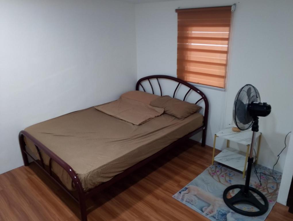 a small bedroom with a bed and a fan at Boarding house in Guinauayan