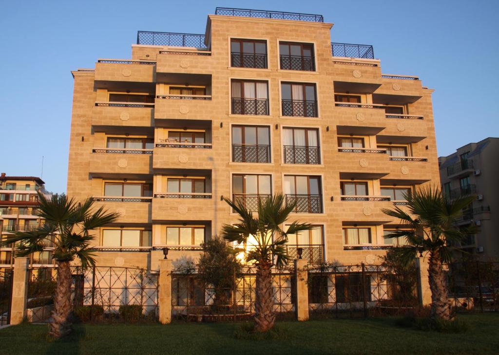 a tall building with palm trees in front of it at Golden Dunes Primorsko Apartments in Primorsko