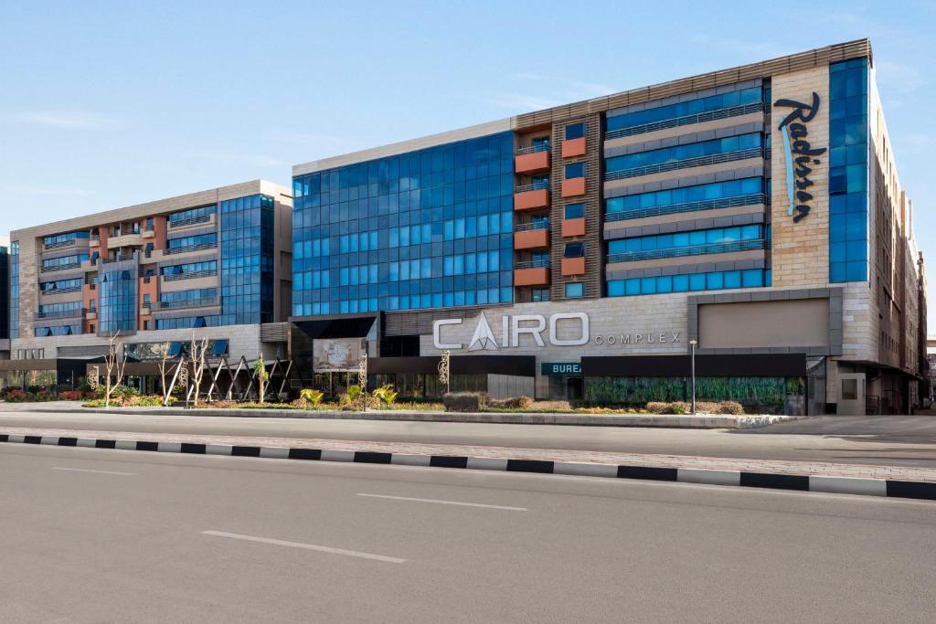 un gran edificio de oficinas con un cartel de carro en él en Radisson Residences Cairo Heliopolis en El Cairo