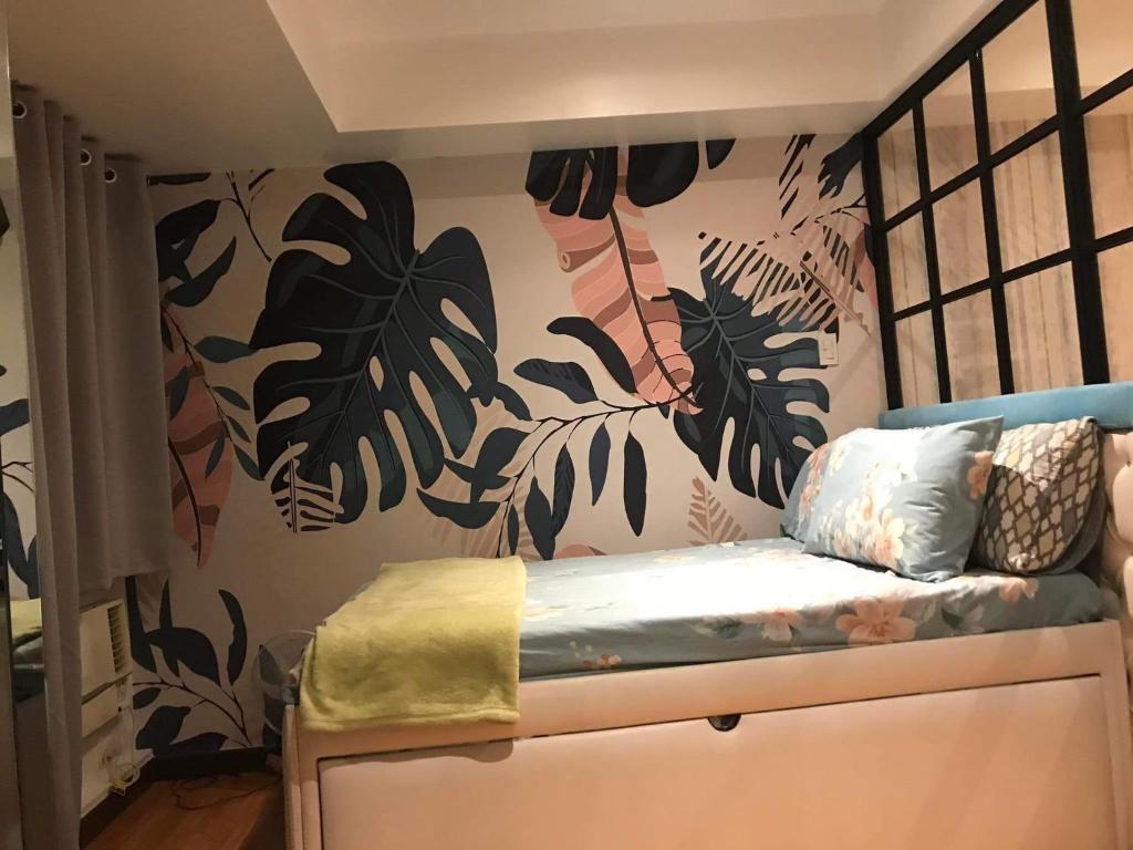 a bedroom with a wall with a mural of plants at Azure Urban Resort Condo Parañaque near NAIA Airport Free Highspeed WIFI and Netflix in Manila