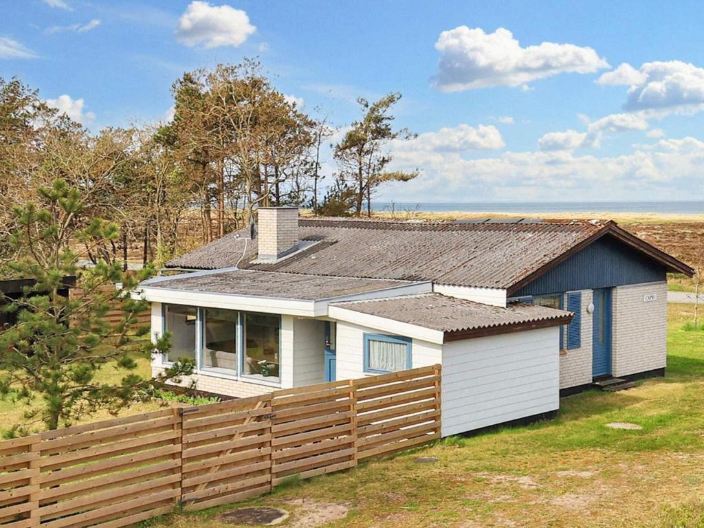 a small house with a fence in front of it at 5 person holiday home in L s in Læsø