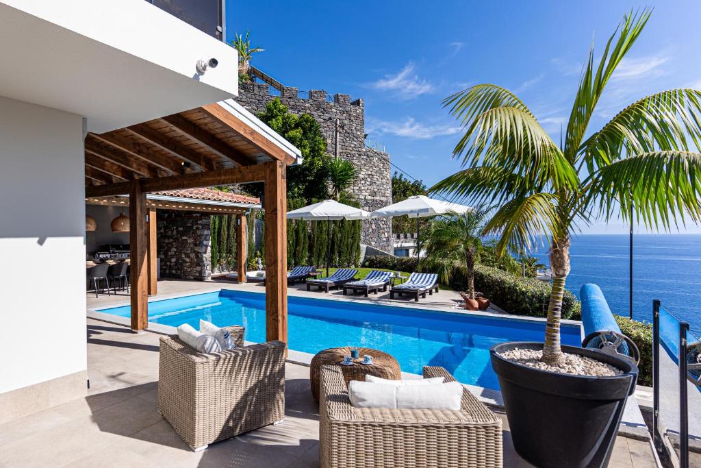 a villa with a swimming pool with a palm tree at GALVÃO HOUSE EXPERIENCE in Ribeira Brava
