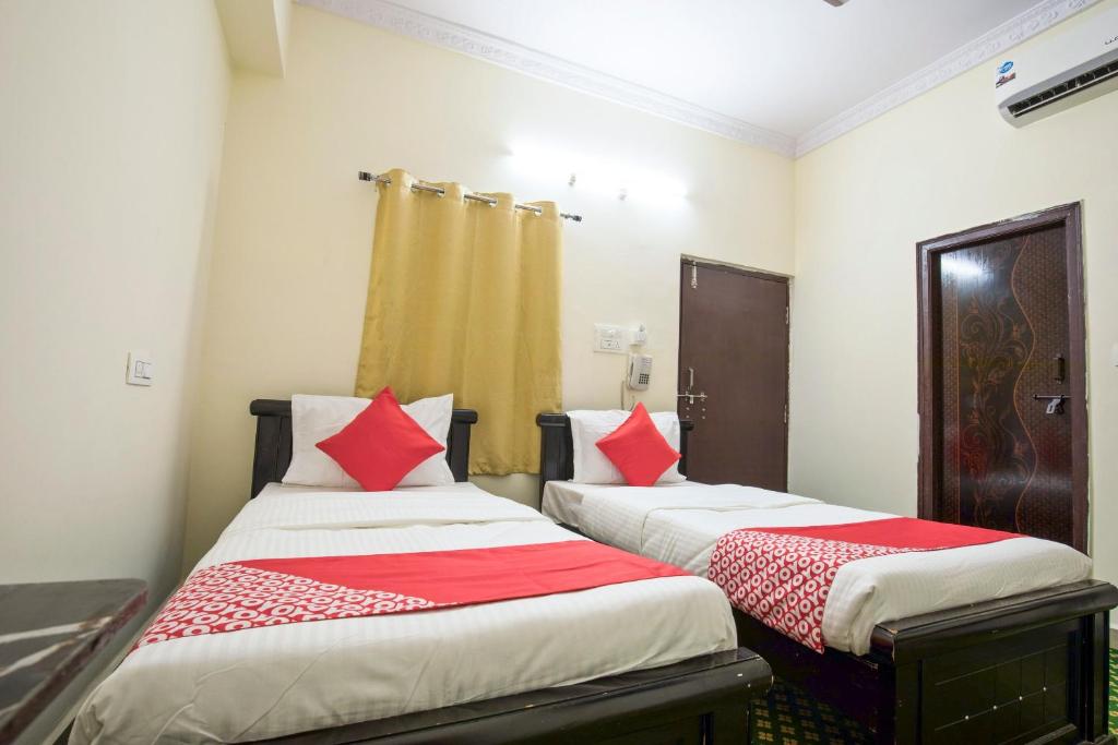 2 łóżka w pokoju z biało-czerwonymi poduszkami w obiekcie OYO Flagship13162 Swiss Legrand w mieście Hajdarabad