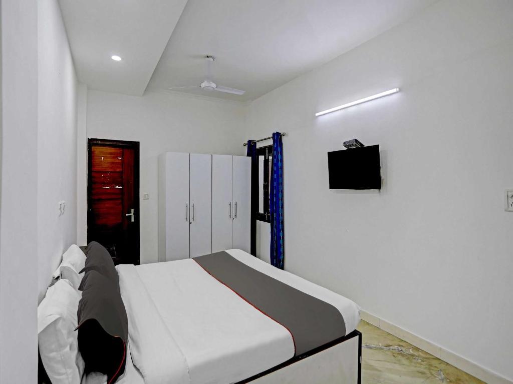 a white bedroom with a bed and a tv at Collection O The Pinaki Residency Near Dlf Avenue Saket in New Delhi