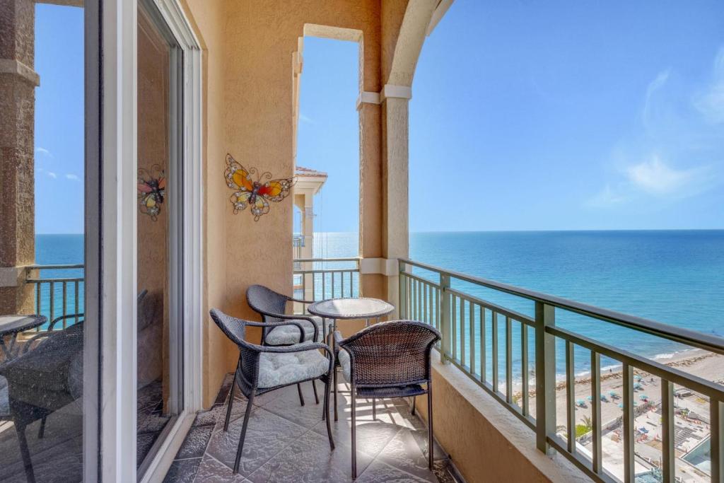 einen Balkon mit Stühlen, Tischen und Meerblick in der Unterkunft 2 BR Monthly beach condo Miami in Hallandale Beach