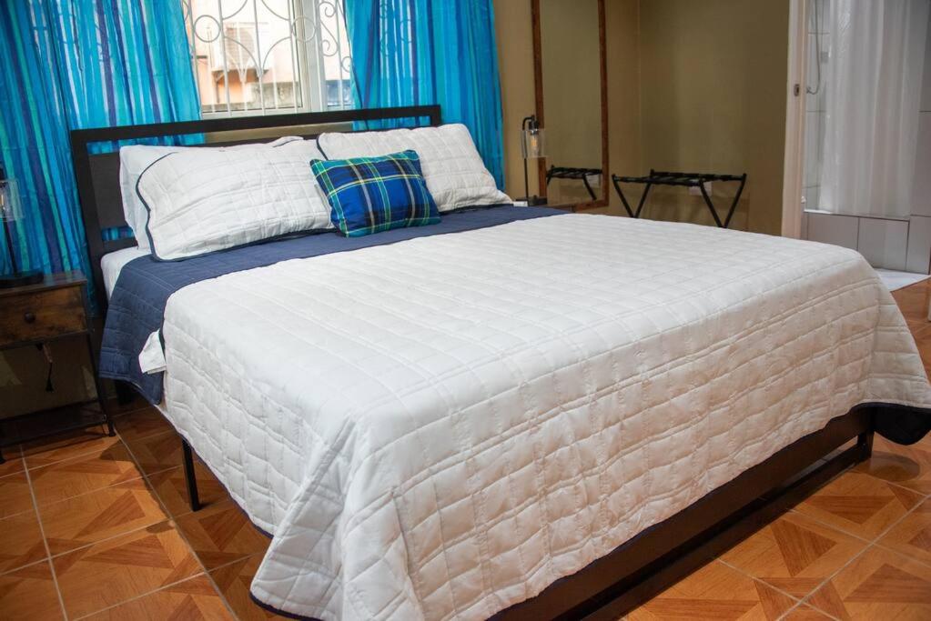 a large bed in a bedroom with blue curtains at Kai Dou in Roseau