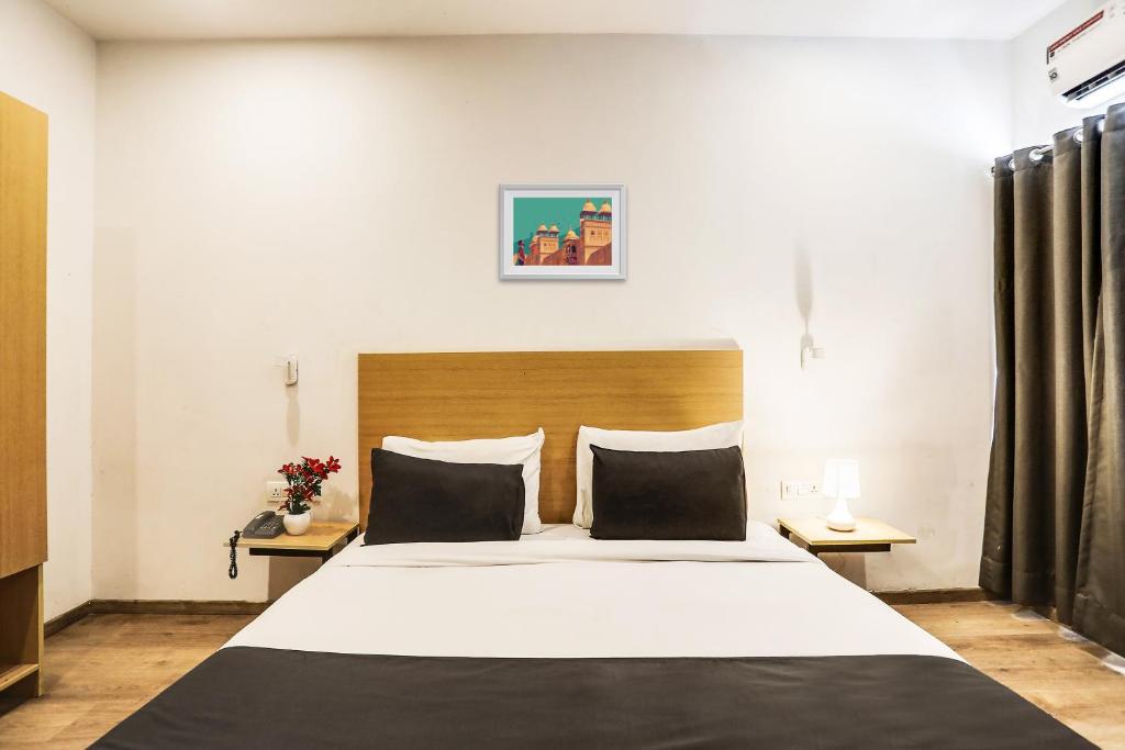 um quarto com uma grande cama branca e duas mesas em Super Townhouse 176 Rajdhani Residency em Surūrnagar