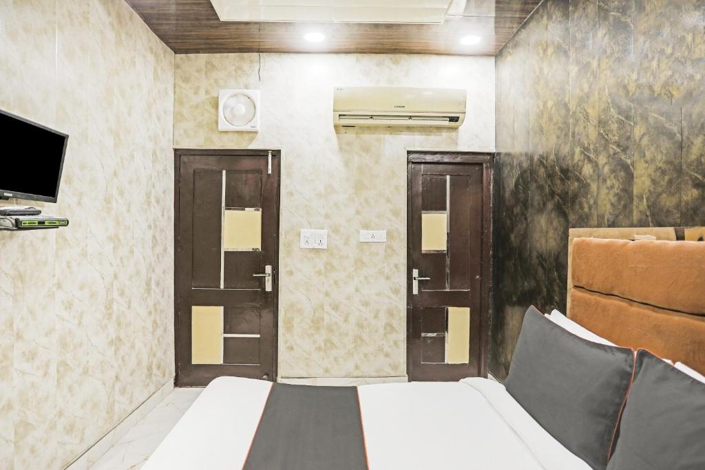 a bedroom with two doors and a bed and a tv at OYO Flagship 80575 Kashish Residency Near Model Town Metro Station in New Delhi
