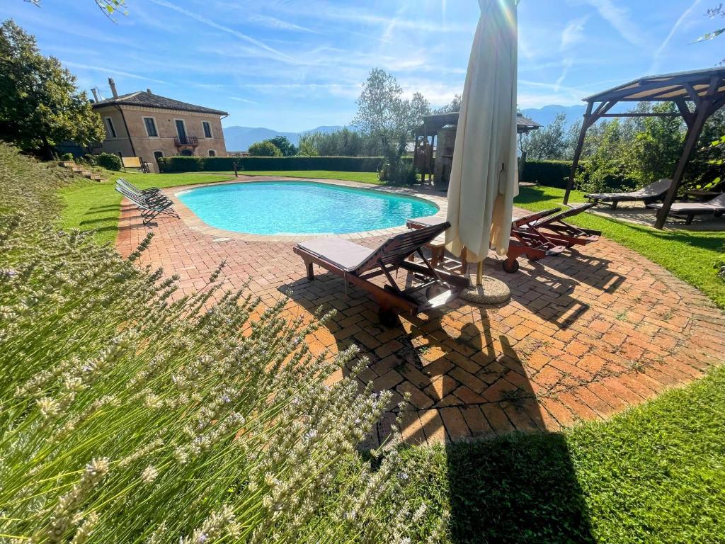 einen Pool mit Sonnenschirm, Tisch und Stühlen in der Unterkunft 04 Pool Villa Spoleto Tranquilla - A sanctuary of dreams and peace 04 in Morro