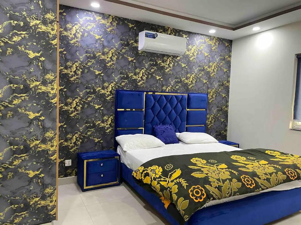 1 dormitorio con cama azul y papel pintado con motivos florales en Hotline Apartments, en Lahore