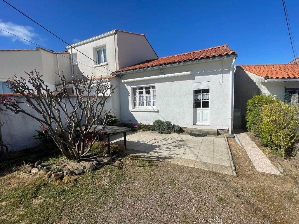 une maison blanche avec un banc devant dans l'établissement Maison de vacances à 900m de la plage avec terrasses, parking, et cuisine équipée - FR-1-22-367, à La Tranche-sur-Mer