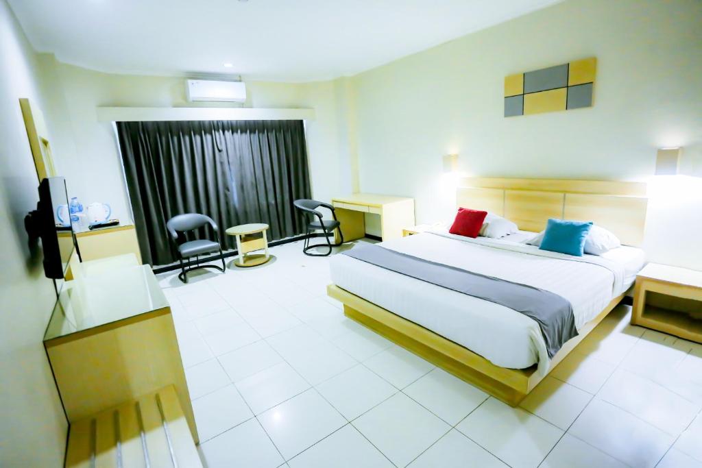 a hotel room with a bed and a desk and chairs at Merpati Hotel in Pontianak