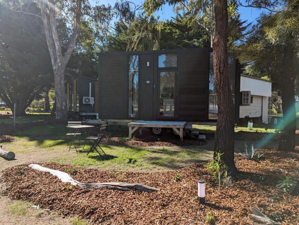 a black tiny house in the woods with a picnic table at Tiny House 19 at Grampians Edge in Dadswells Bridge