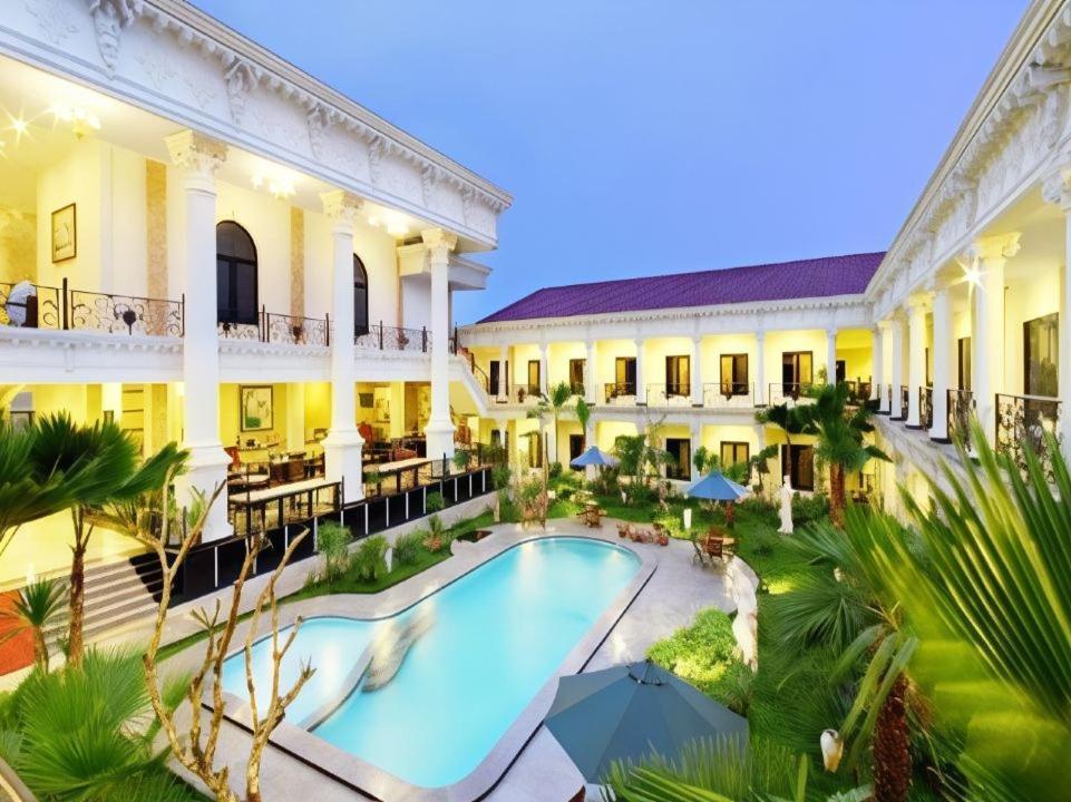 een uitzicht op een gebouw met een zwembad bij The Grand Palace Hotel Yogyakarta in Yogyakarta