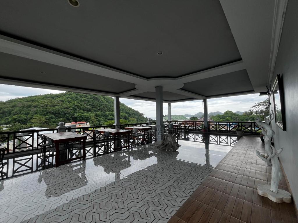 a room with tables and chairs on a balcony at SUNRISE HOTEL LABUAN BAJO in Labuan Bajo