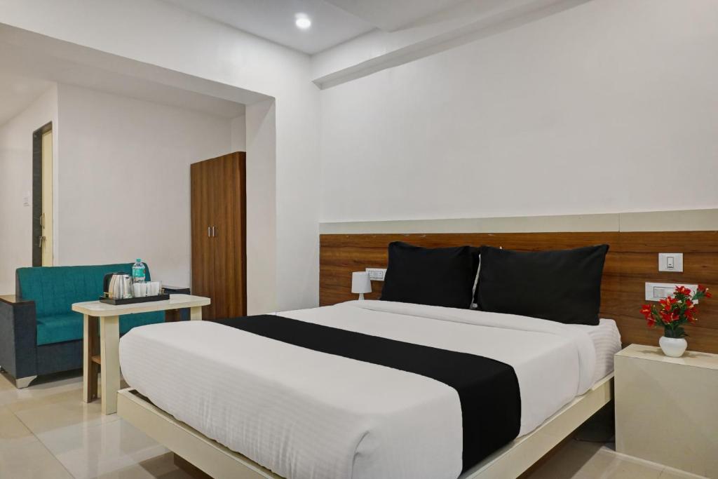 a bedroom with a large bed and a blue chair at Collection O Hotel Stay Prime Baner in Pune