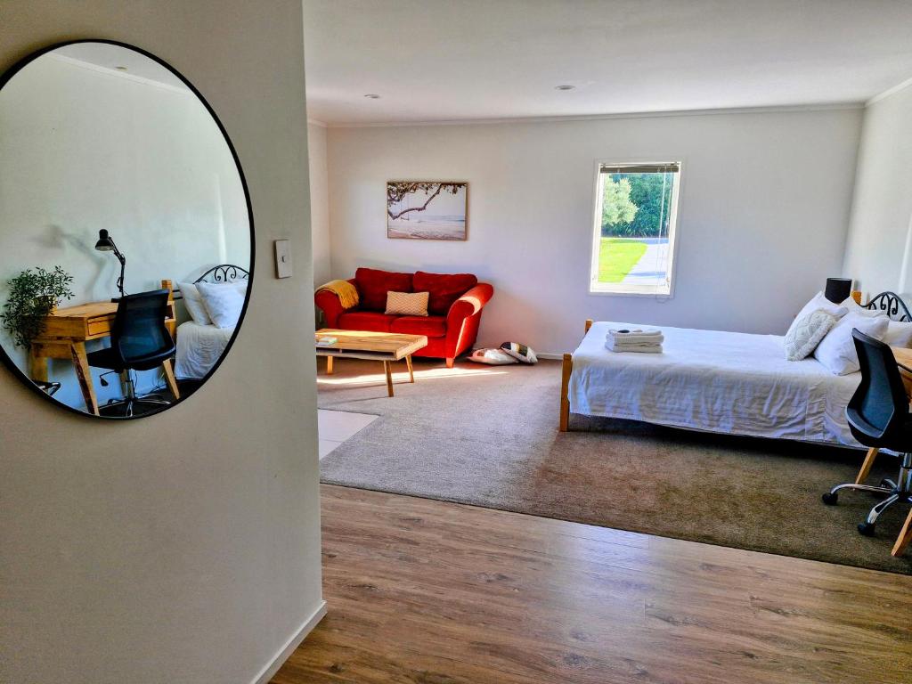 1 dormitorio con cama y espejo en Peace and Aroha Mangawhai - Apartment, en Mangawhai