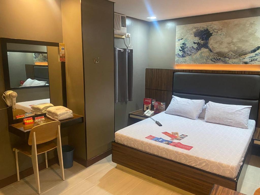 a bedroom with a bed and a table and a mirror at Hotel Sogo Malate in Manila