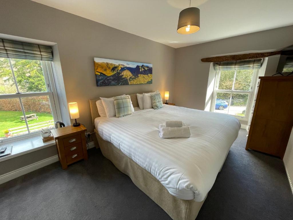a bedroom with a large white bed with two windows at Royal Hotel in Dockray