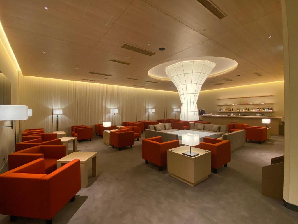 ein Restaurant mit orangefarbenen Stühlen und Tischen und einem Kronleuchter in der Unterkunft Kaisenkaku in Aomori