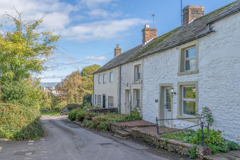 an old white stone house with a driveway at L'al Cottage, Sockbridge in Penrith