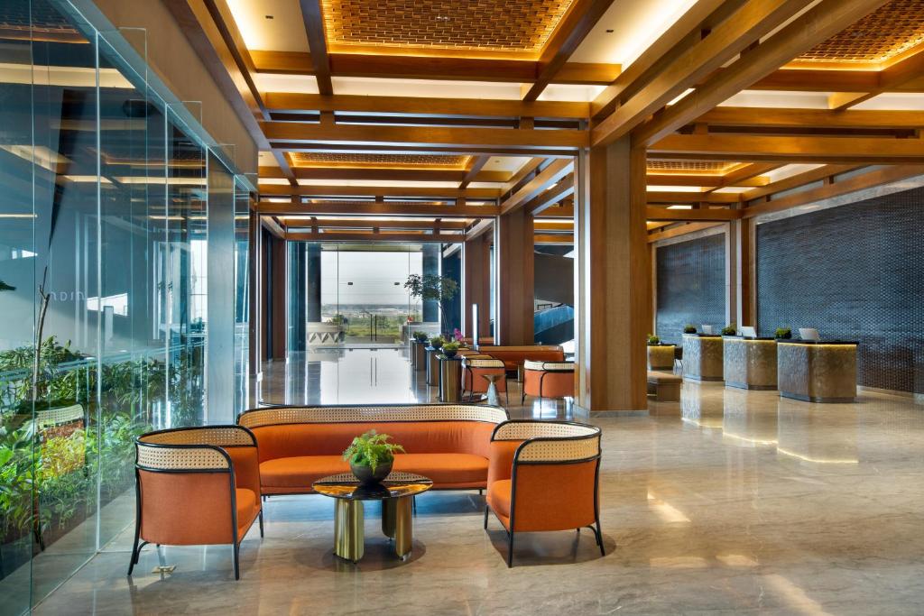 a lobby with orange chairs and tables and windows at MORAZEN Yogyakarta in Temon