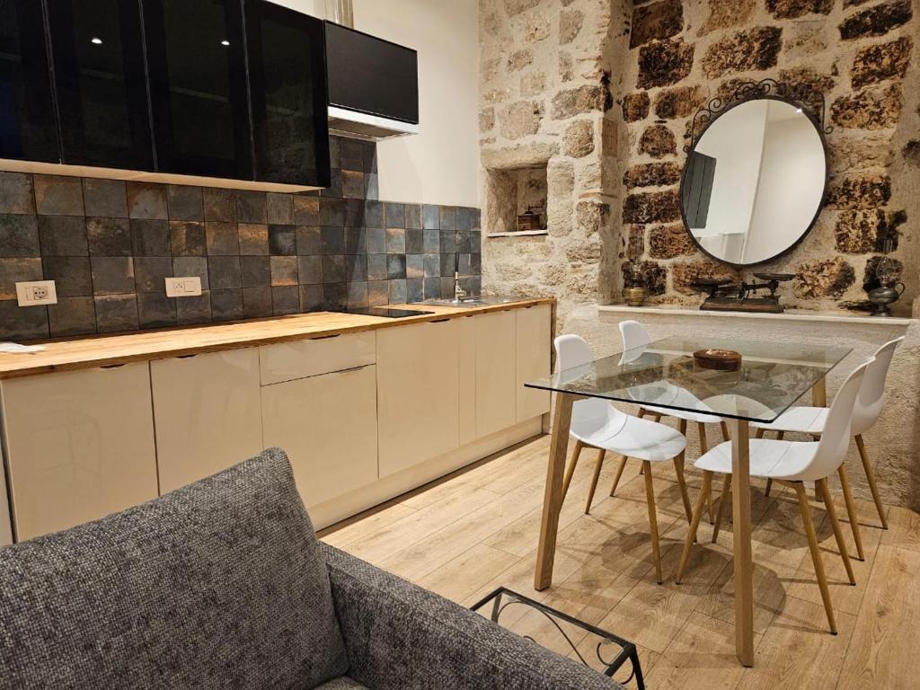 cocina con mesa de cristal y sillas blancas en Le Beffroi Hôtel & Apart, en Tournon-dʼAgenais