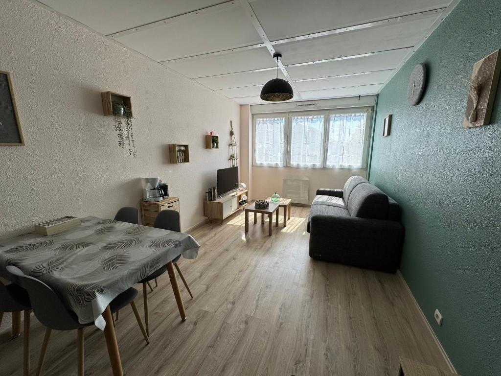 Appartement rénové tout confort, centre Valdahon في Le Valdahon: غرفة معيشة مع أريكة وطاولة