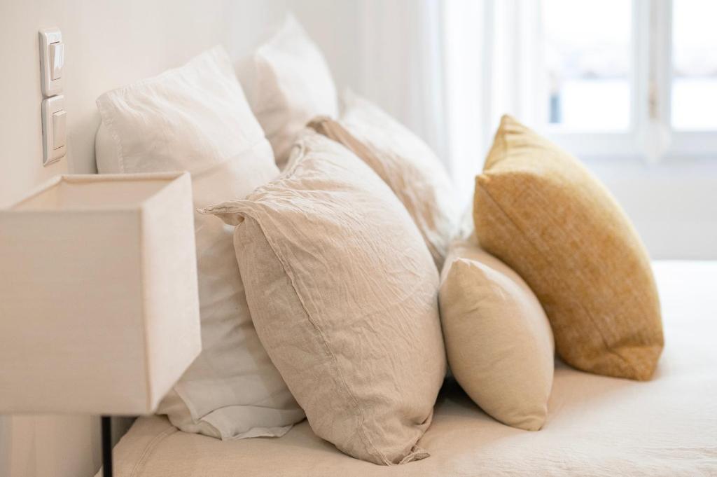 a pile of white pillows sitting on a bed at La Tropézienne - appartement au cœur du village in Saint-Tropez