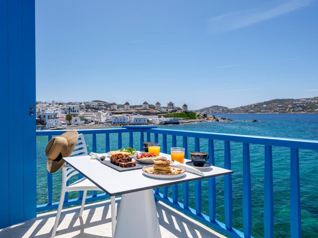 einen Tisch mit Speisen auf einem Balkon mit Blick auf das Wasser in der Unterkunft Bluetopia Suites in Mykonos Stadt