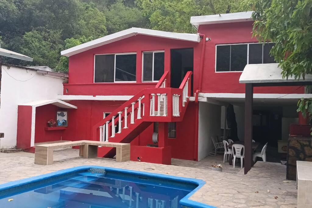 a red house with a staircase and a swimming pool at Quinta Los Tercos in Santiago