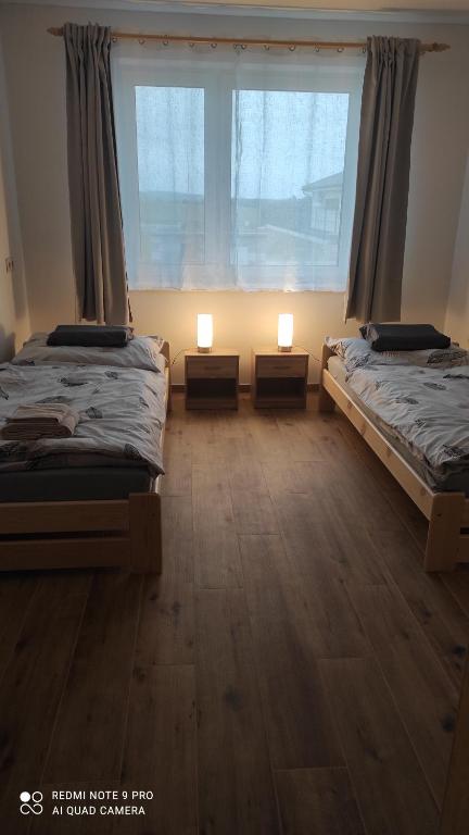 2 Betten in einem Zimmer mit einem großen Fenster in der Unterkunft Privát Ivanka in Levice