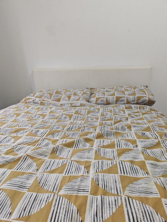 a bed in a room with a white and yellow comforter at Spacious flat with free parking in Croydon in Croydon
