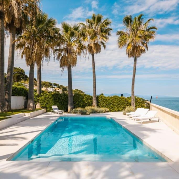 une piscine avec des palmiers et l'océan dans l'établissement Villa Boat Luxe, à Antibes