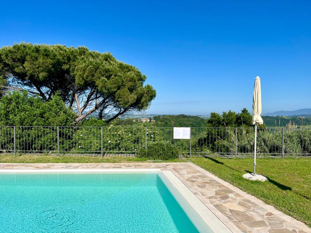 a swimming pool in front of a fence with a tree at Borgo di Libbiano in Libbiano
