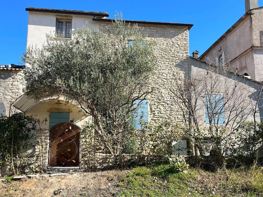 une maison en pierre avec une grande porte et un arbre dans l'établissement Charmant appartement St Florent T4, à Saint-Florent