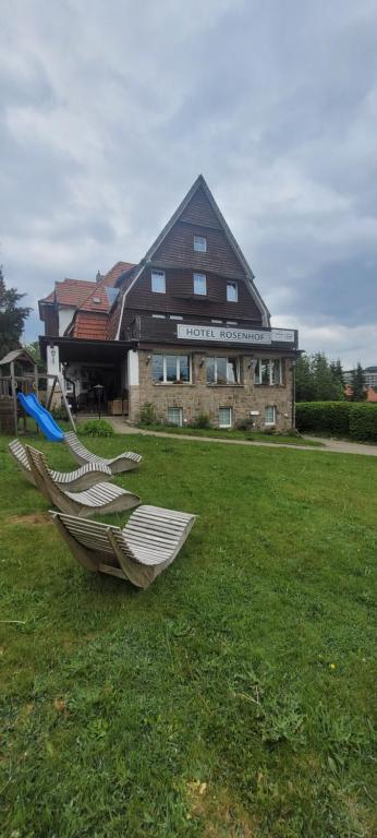 un bâtiment avec un banc dans l'herbe devant dans l'établissement Hotel Rosenhof Braunlage, à Braunlage