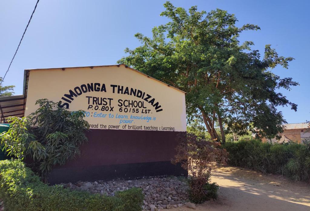 um sinal para uma escola de confiança em frente a um edifício em Simoonga Thandizani School em Livingstone