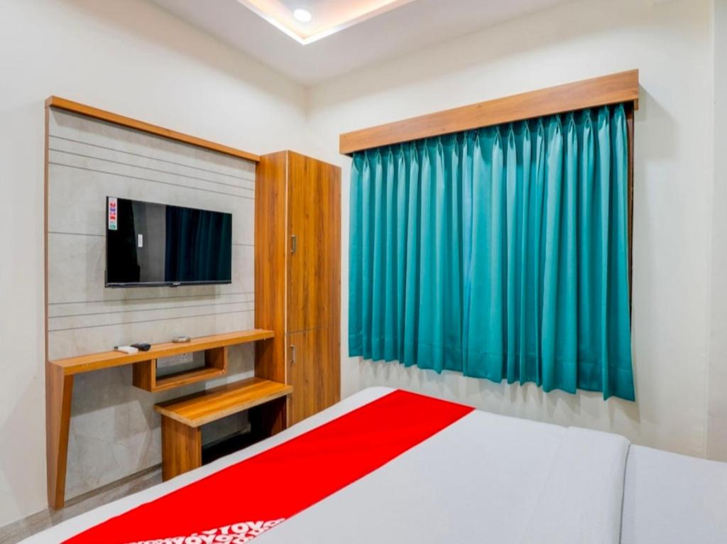 ein Schlafzimmer mit einem Bett und einem TV in der Unterkunft Hotel Hill View in Gandhinagar