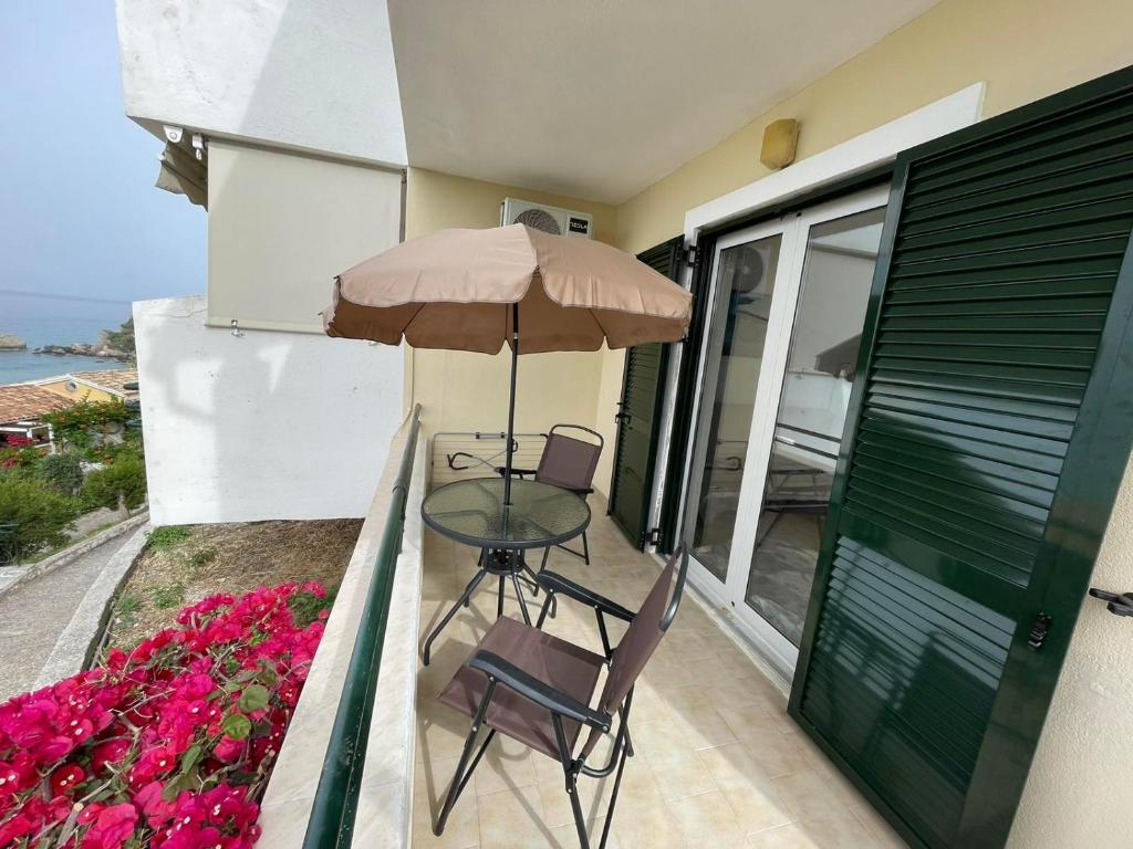 Beach 'Glyfada' apartment 118 في غليفادا: طاولة وكراسي على شرفة مع مظلة
