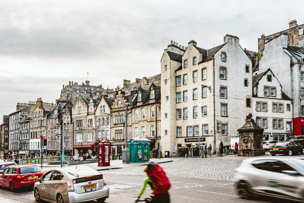 Grassmarket Hotel في إدنبرة: امرأة تقطع شارع في مدينة فيها سيارات