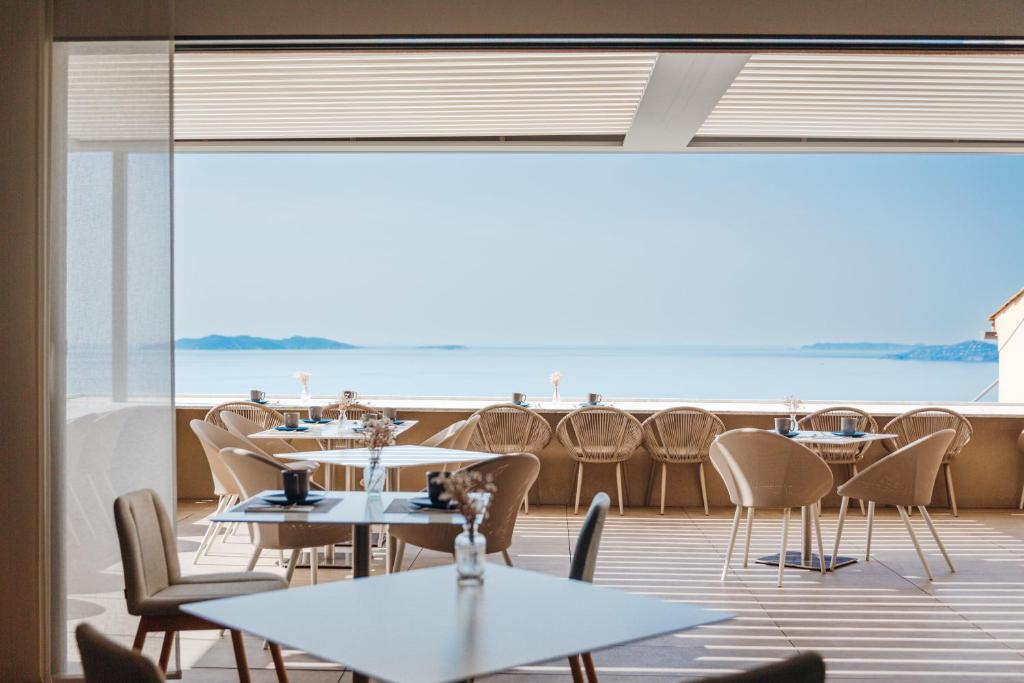 a restaurant with tables and chairs and a large window at Hôtel La Villa Douce in Rayol-Canadel-sur-Mer