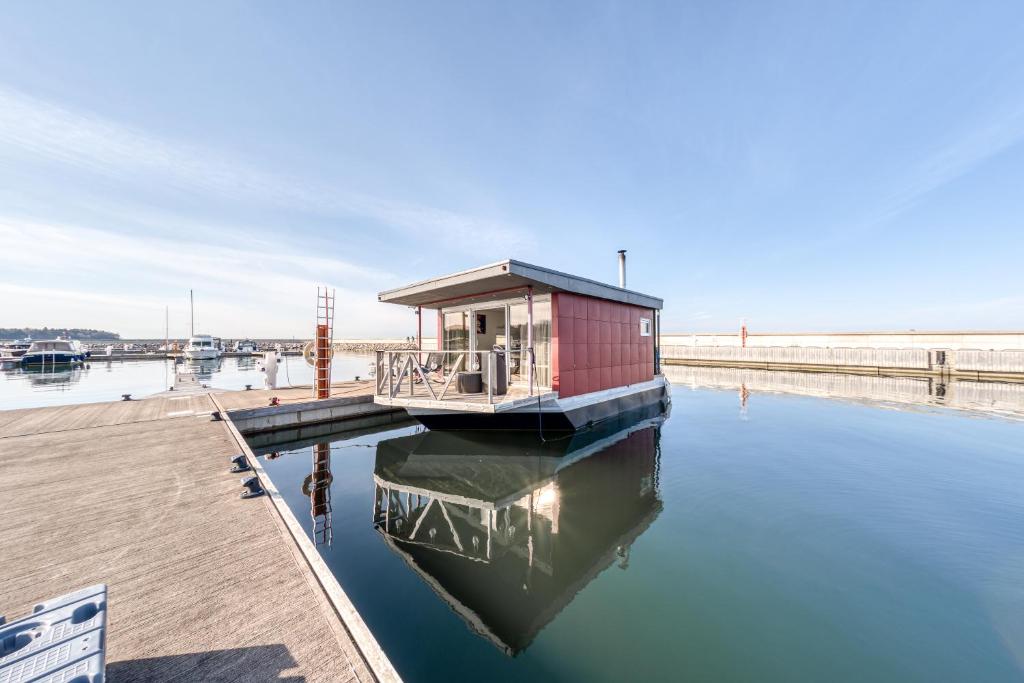 a small boat in the water next to a dock at Cozy Floating house with sauna in Tallinn