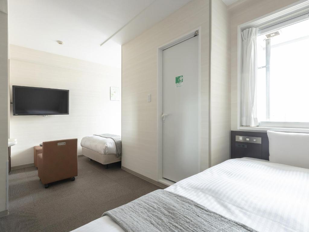 a hotel room with two beds and a television at Vessel Inn Hiroshima Ekimae in Hiroshima