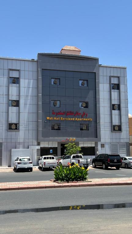 a building with cars parked in a parking lot at شقق وافي حائل للشقق المخدومة إقتصادي in Hail
