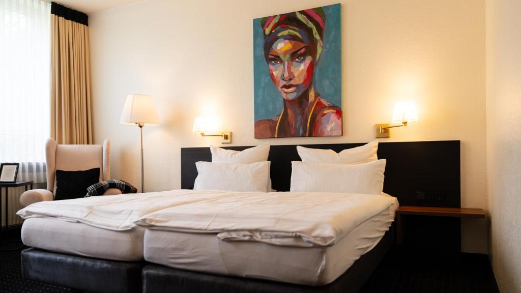 a bedroom with a large bed with a painting on the wall at Parkhotel Cloppenburg in Cloppenburg