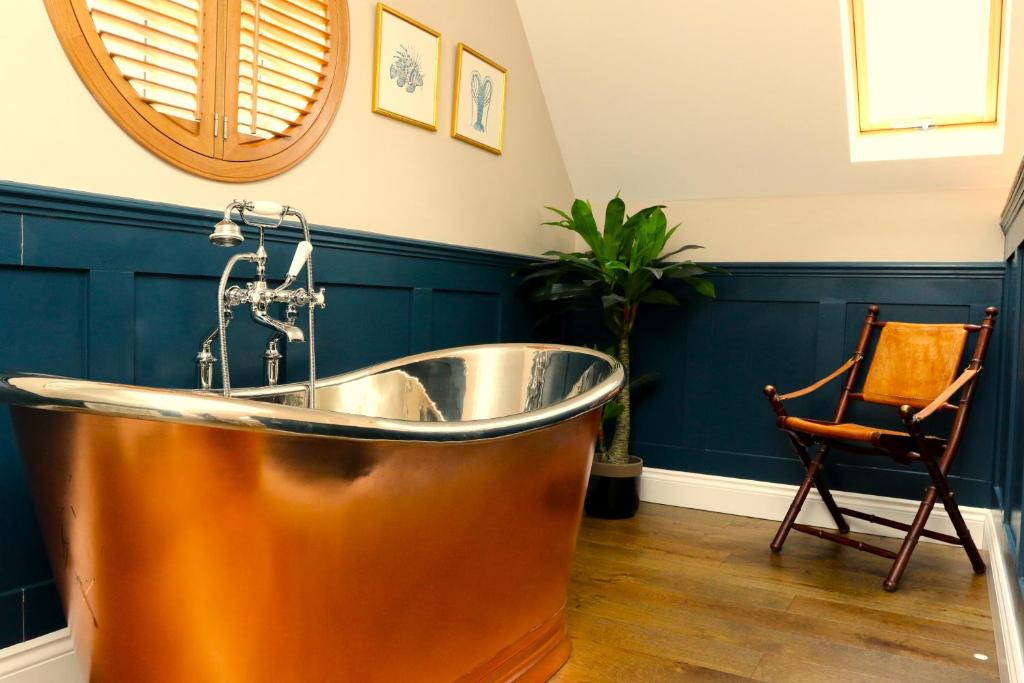 een koperen bad in een badkamer met een stoel bij The Loft at the Croft - Stunning rural retreat perfect for couples & dogs in Leigh